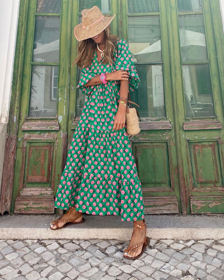 Pink floral green long dress with straw hat accessorized, standing against vintage green doors.