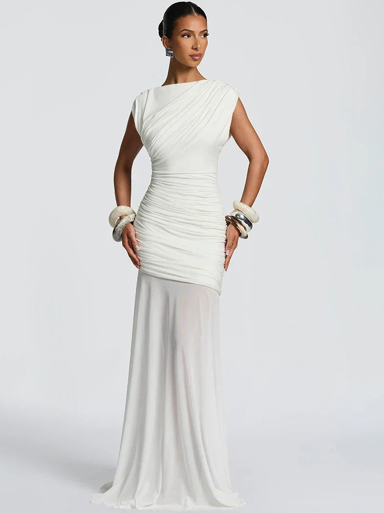 Elegant white gown with ruched details and sheer skirt, accessorized with chunky bracelets, in a studio setting.