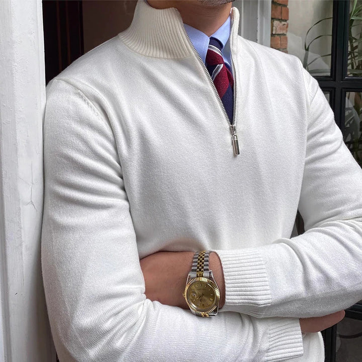 Close-up of white half-zip sweater with shirt and tie, featuring a watch, near a door and brick wall.