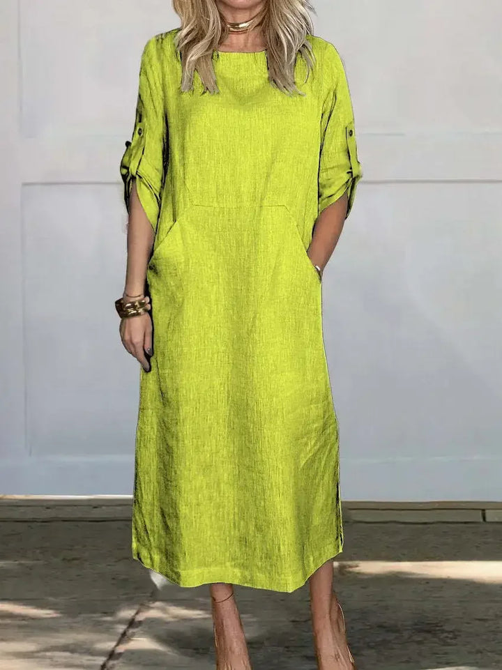 Lime A-line loose fit draped evening dress, studio setting with wooden floor and pale wall background.