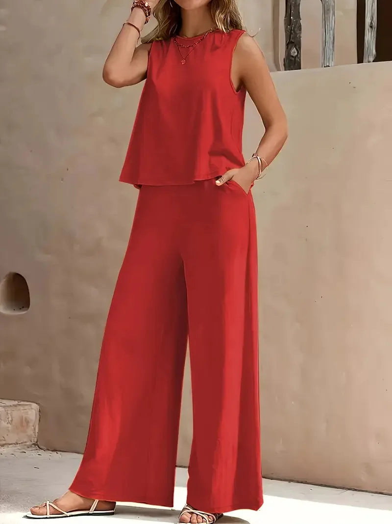 Red sleeveless two-piece set with wide-leg pants, styled outdoors against a beige wall.