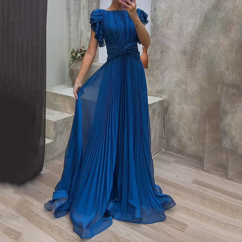 Stunning blue pleated evening dress featuring ruffled sleeves, displayed in a stylish indoor setting with minimalist decor.