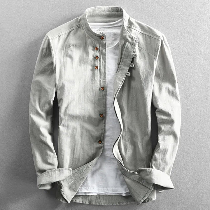 Light gray long-sleeve shirt with a stand collar and brown buttons, layered over a white shirt on a gray background.
