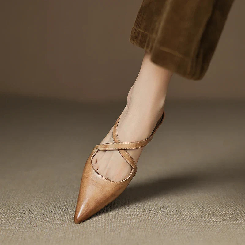 Side view of tan mules with criss-cross straps, foot slightly lifted.