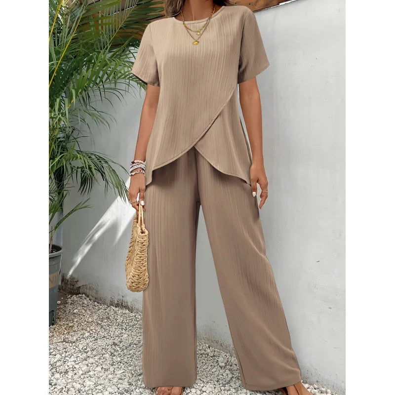 Beige two-piece set featuring a soft, flowing short-sleeve top and wide-leg pants, modeled outdoors with tropical plants.