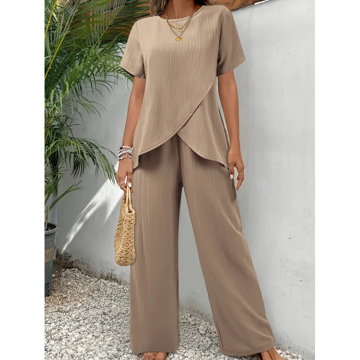 Beige two-piece set featuring a soft, flowing short-sleeve top and wide-leg pants, modeled outdoors with tropical plants.