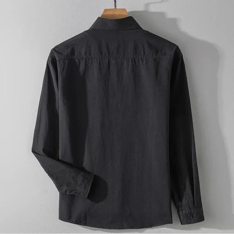 Back view of dark charcoal shirt with long sleeves on wooden hanger, gray studio background.