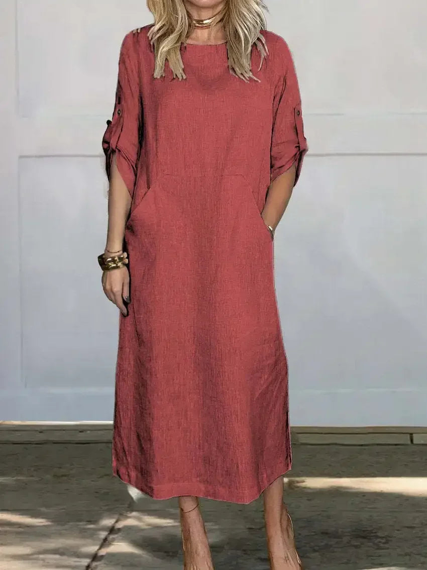 Red A-line loose fit draped evening dress, studio setting with wooden floor and pale wall background.
