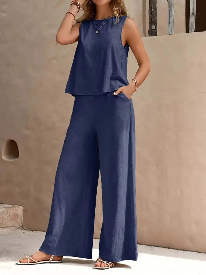 Blue sleeveless two-piece set with wide-leg pants, styled outdoors against a beige wall.