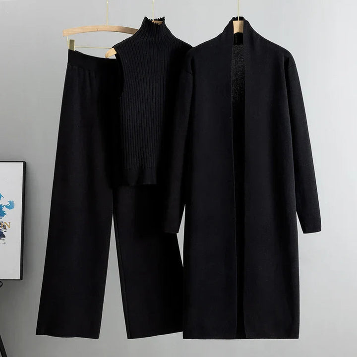Black three-piece set including sleeveless ribbed top, wide-leg pants, and long open cardigan on hangers in a studio setting.