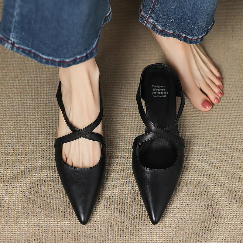 Person standing barefoot next to worn black mule on carpet.