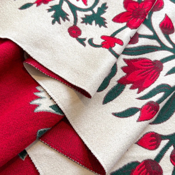 Close-up of red and green floral patterned scarf with white background.
