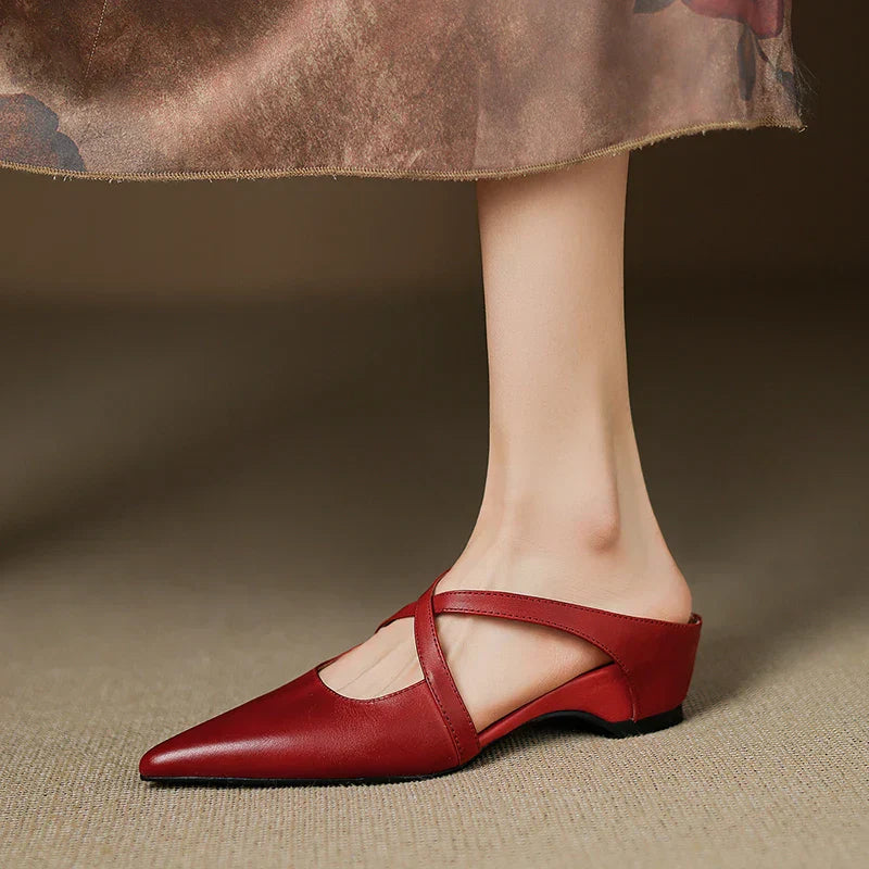 Side view of red mules with criss-cross straps, worn with a floral skirt.