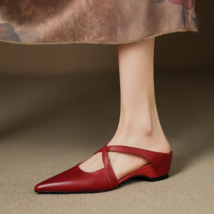 Side view of red mules with criss-cross straps, worn with a floral skirt.