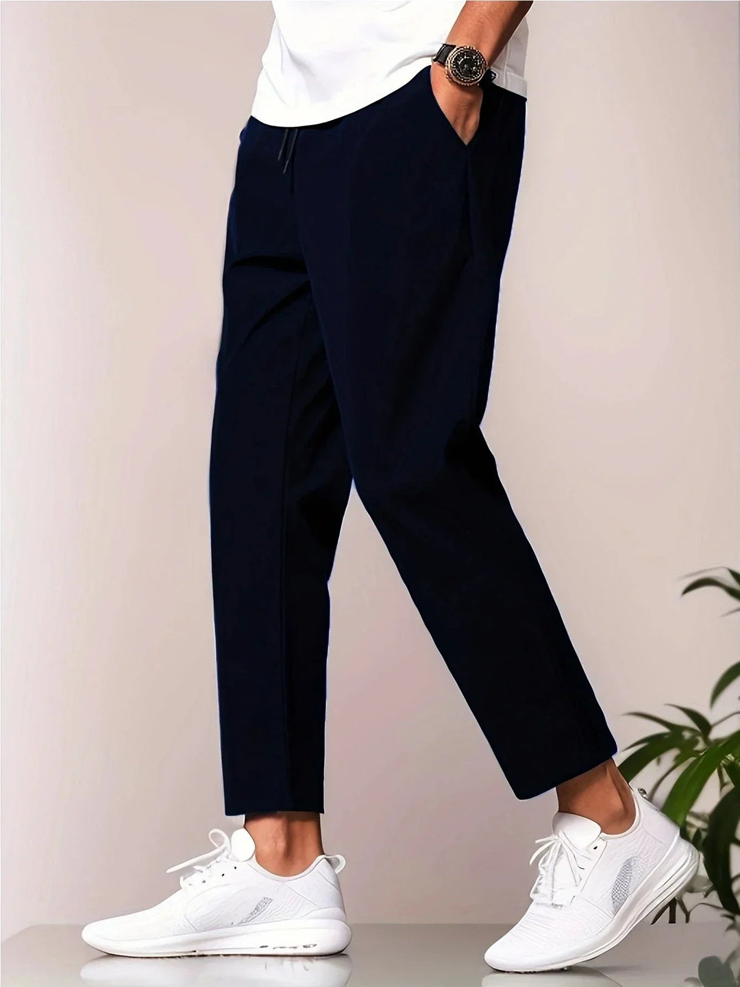 Smart navy trousers matched with a white tee and white sneakers, in a studio environment.