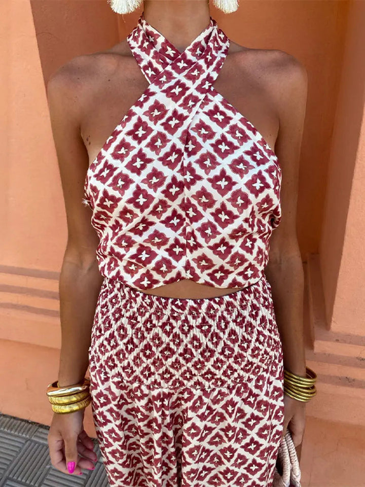 Close-up of red and white patterned halter top and pants, worn by woman with gold bangles, standing against orange wall.