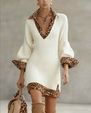 White dress with leopard print collar and cuffs, long sleeves, gold jewelry, and matching handbag in a neutral studio setting.