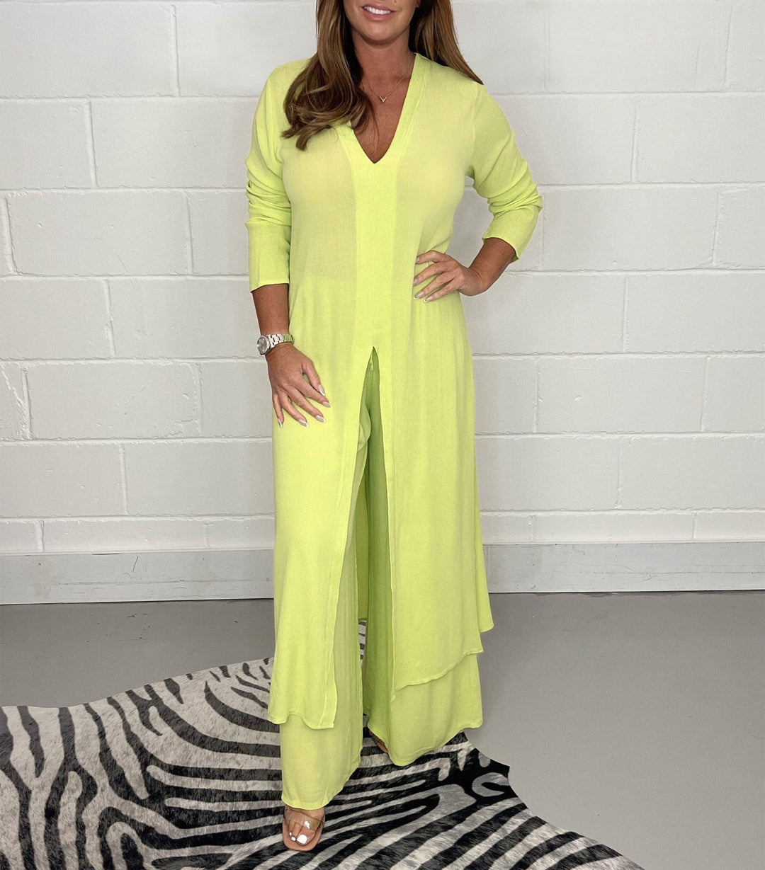 Lime green two-piece set with long sleeves, V-neck, and flowing pants in a studio with zebra rug.