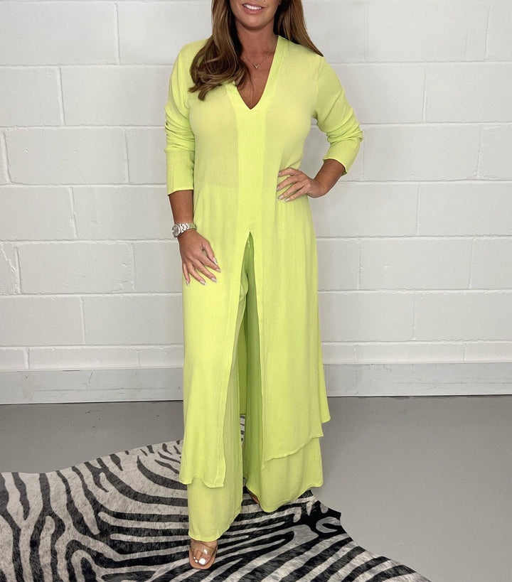 Lime green two-piece set with long sleeves, V-neck, and flowing pants in a studio with zebra rug.