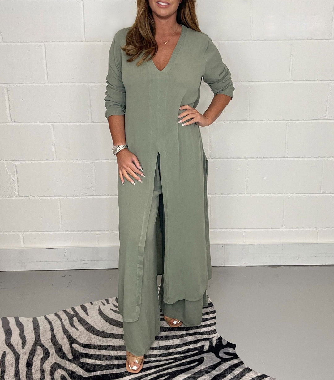Olive green two-piece set with long sleeves, V-neck, and flowing pants in a studio with zebra rug.