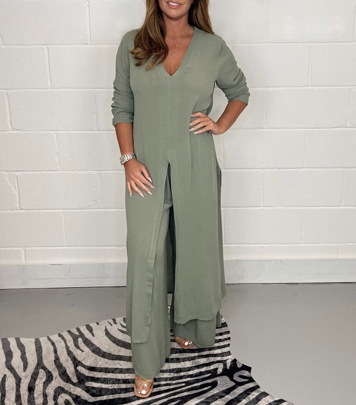 Olive green two-piece set with long sleeves, V-neck, and flowing pants in a studio with zebra rug.