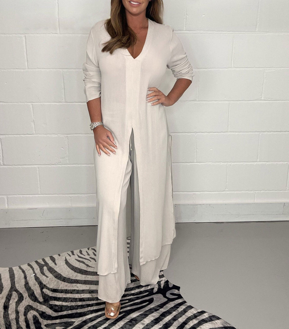 Light beige two-piece set with long sleeves, V-neck, and flowing pants in a studio with zebra rug.