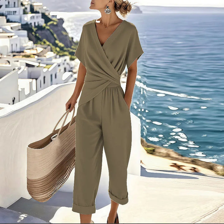 Chic olive two-piece set with wrap top, capri pants, and large woven tote, overlooking sea and white terraces.