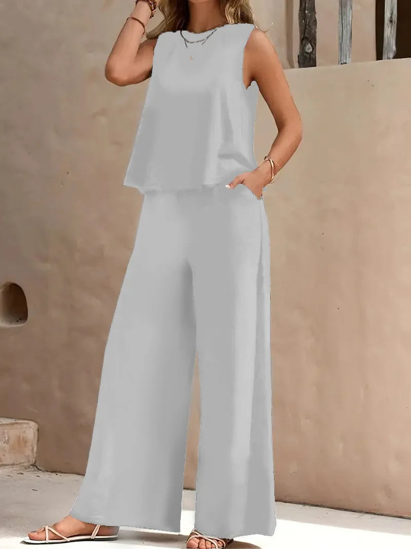 Light gray sleeveless two-piece set with wide-leg pants, styled outdoors against a beige wall.