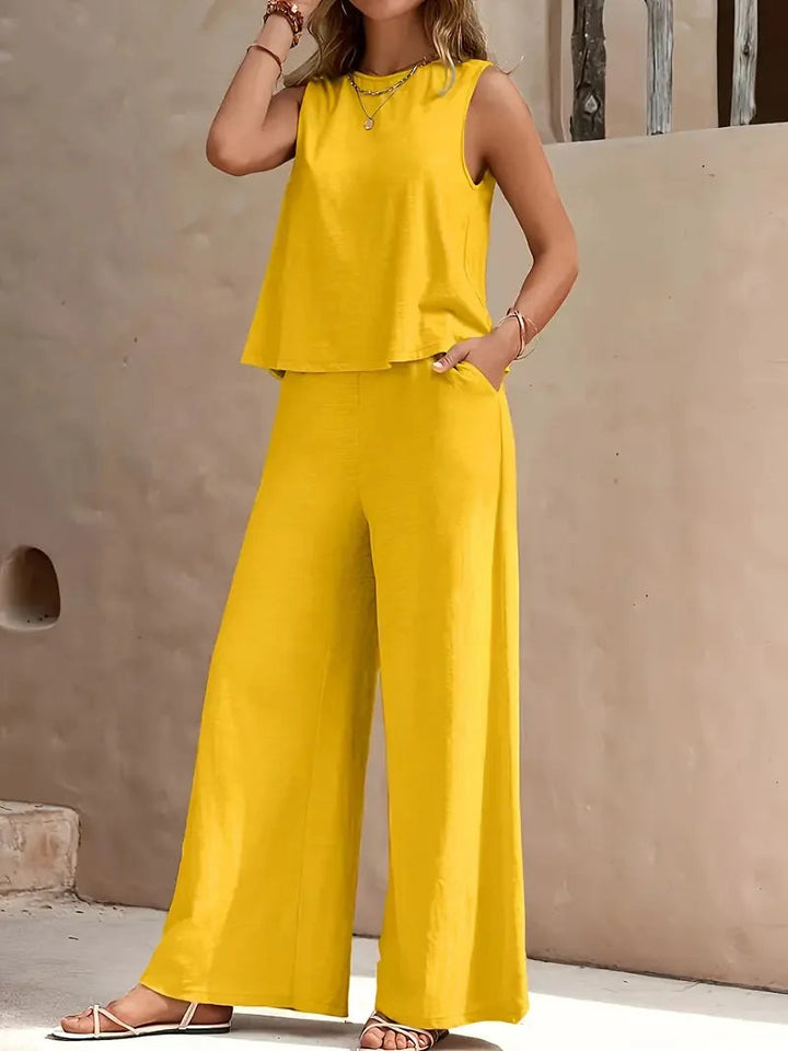 Yellow sleeveless two-piece set with wide-leg pants, styled outdoors against a beige wall.