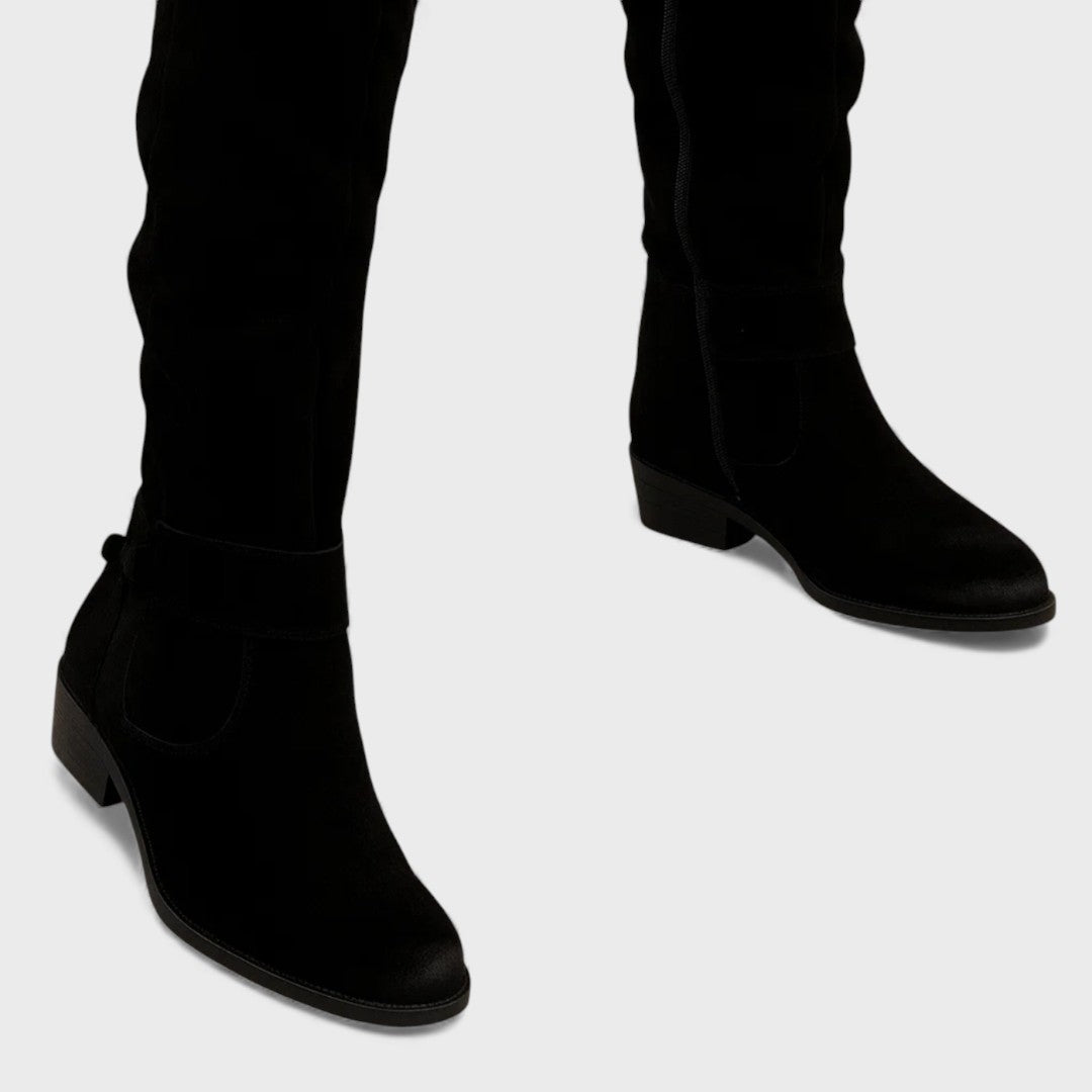 Close-up of black knee-high boots with buckle detail and heels, studio background.