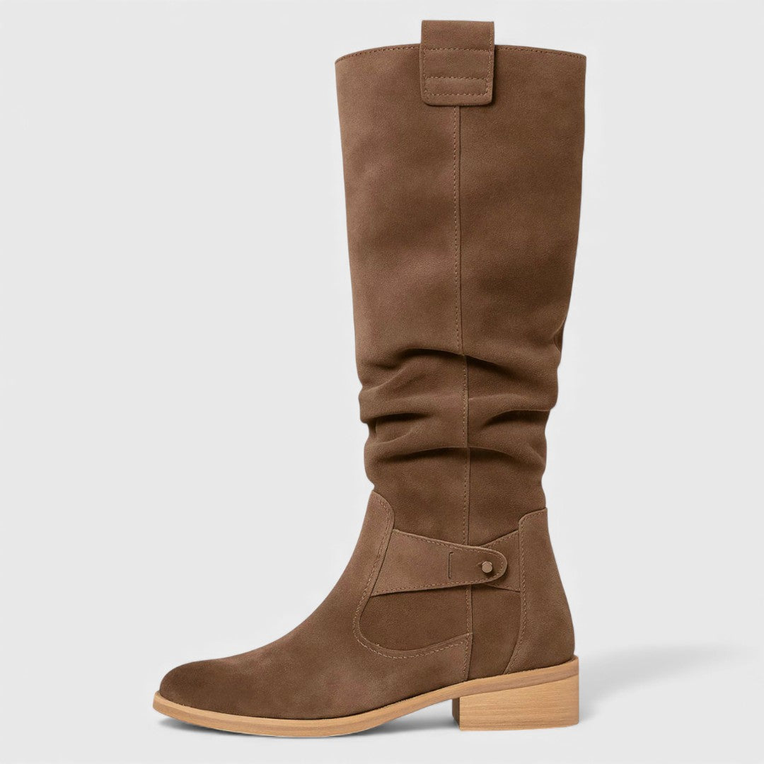Single brown knee-high boot with buckle detail on a wooden heel, studio background.