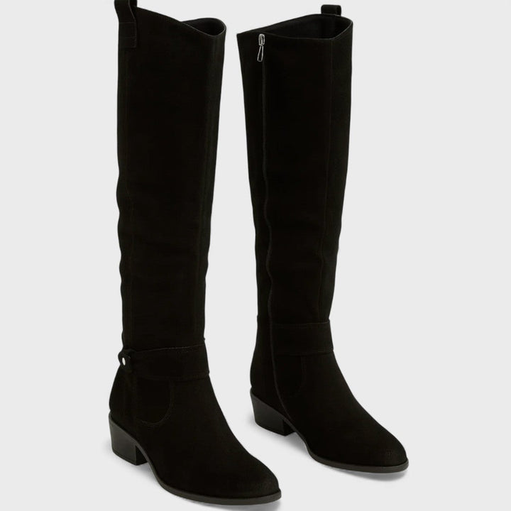 Pair of black knee-high boots with buckle detail, zipper, and heels, studio background.