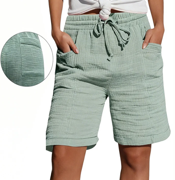 Light green Bermuda shorts with elastic waist, drawstring, pockets, and textured fabric. Modeled outdoors.