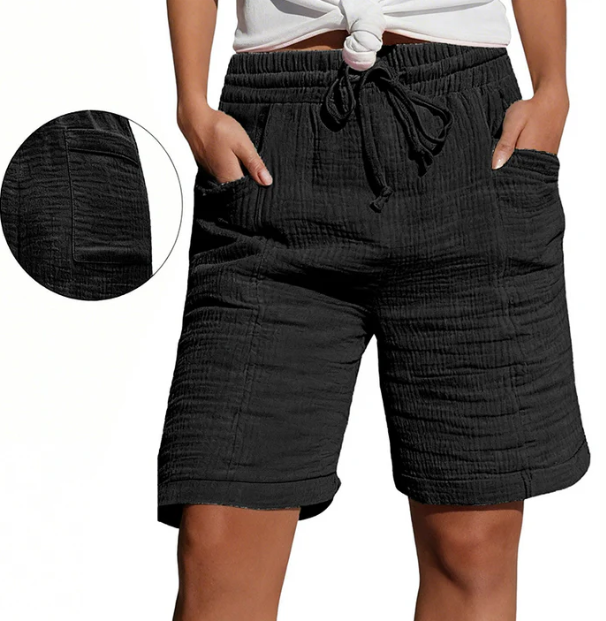 Black Bermuda shorts with elastic waist, drawstring, pockets, and textured fabric. Modeled outdoors.