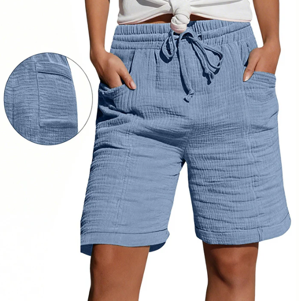 Blue Bermuda shorts with elastic waist, drawstring, pockets, and textured fabric. Modeled outdoors.