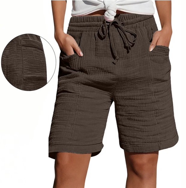 Brown Bermuda shorts with elastic waist, drawstring, pockets, and textured fabric. Modeled outdoors.