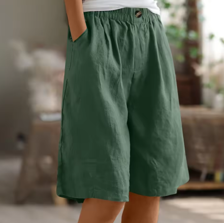 Forest green comfort shorts featuring an elastic waistband and pockets, in a cozy indoor setting.