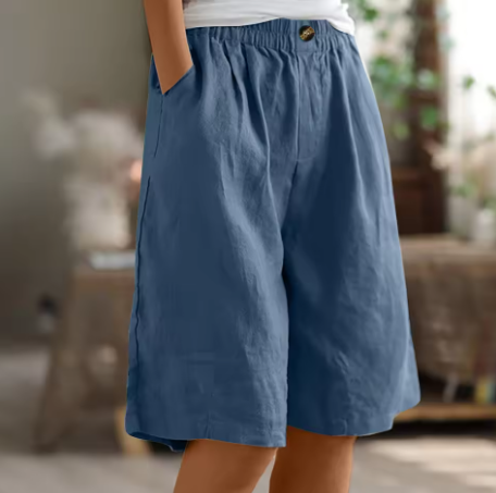Blue comfort shorts with elastic waist and pockets in a softly lit, homey indoor scene.