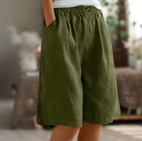 Olive green comfort shorts with elastic waistband and pockets in a cozy indoor setting with soft lighting.