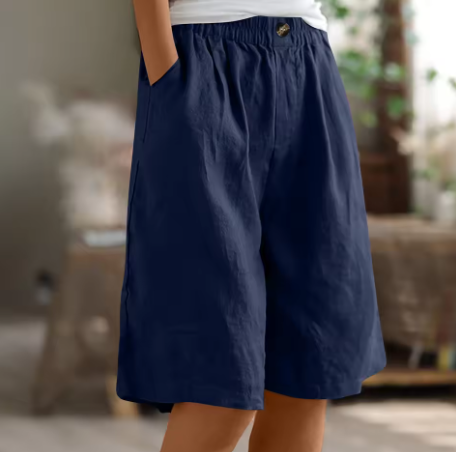 Navy blue comfort shorts with elastic waist and pockets, set in a softly lit indoor space.