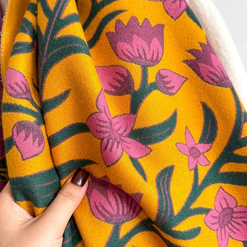 Close-up of a hand holding a colorful botanical scarf with floral patterns.