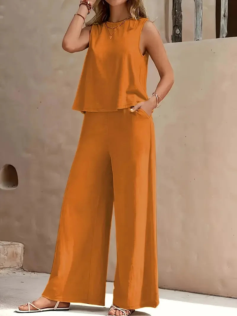 Orange sleeveless two-piece set with wide-leg pants, styled outdoors against a beige wall.