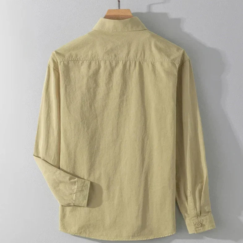 Back view of light tan shirt with long sleeves on wooden hanger, gray studio background.