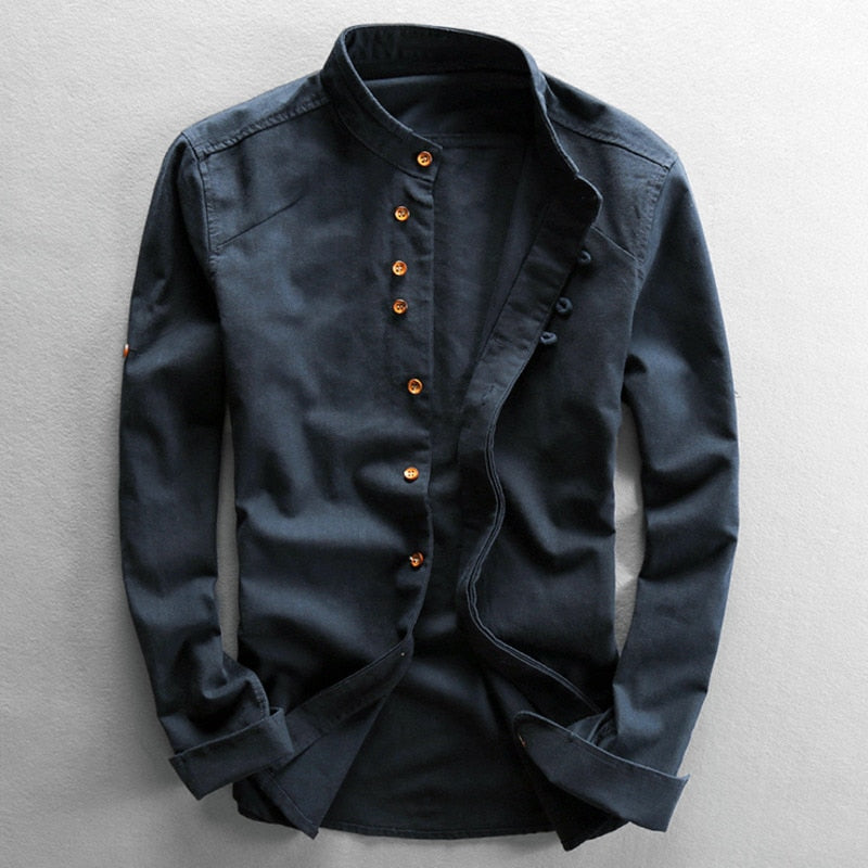 Dark blue long-sleeve shirt with a stand collar and brown buttons, displayed on a light gray studio background.