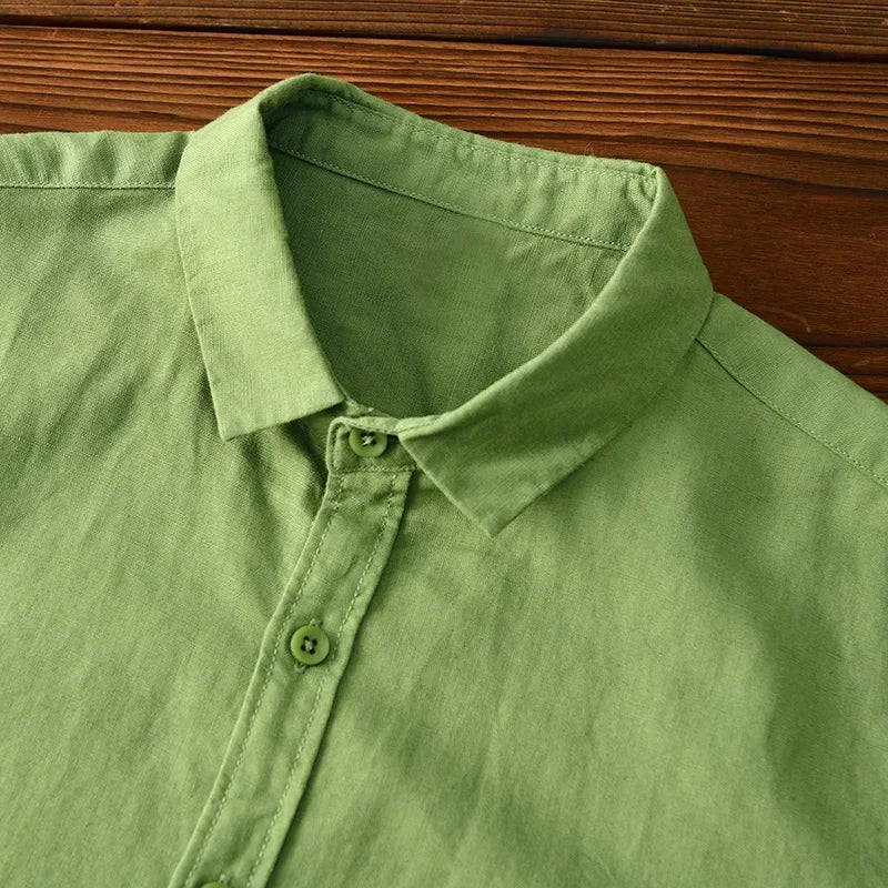 Close-up of green linen shirt collar and buttons on wooden surface.