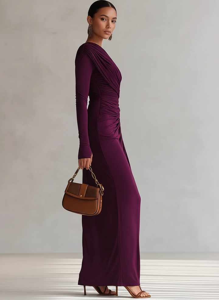 Side view of purple maxi dress with gathered detail, brown handbag, and heels in a simple studio environment.