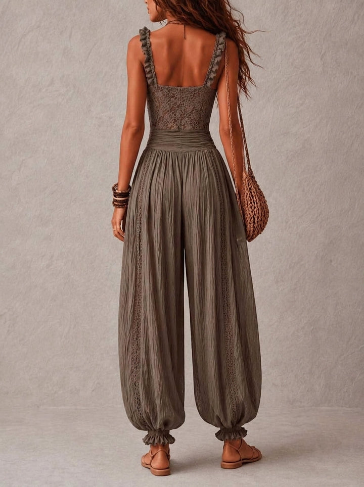 Back view of a woman wearing a lace top with pleated pants, holding a woven bag, in a neutral-toned studio environment.
