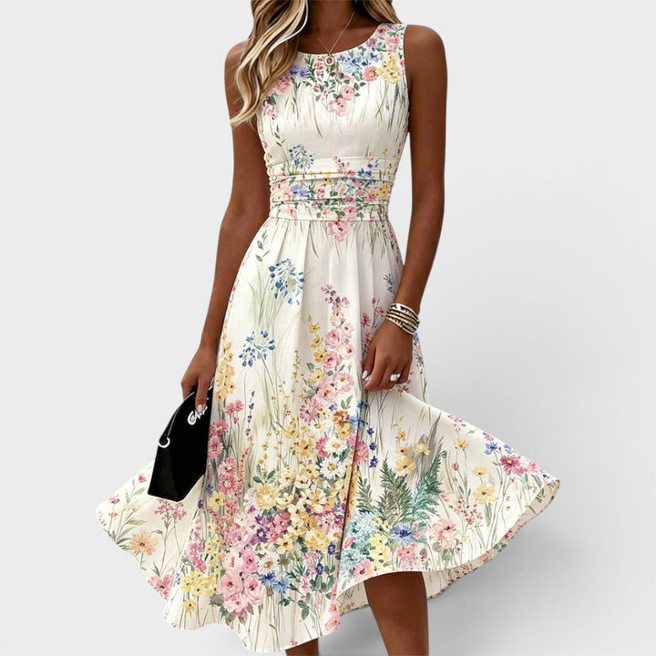 Sleeveless midi dress with floral print, fitted waist, flowing skirt. Model holding clutch against plain background.