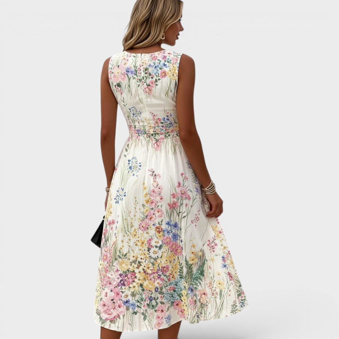 Back view of sleeveless floral midi dress with a fitted waist. Model turned slightly, plain background.