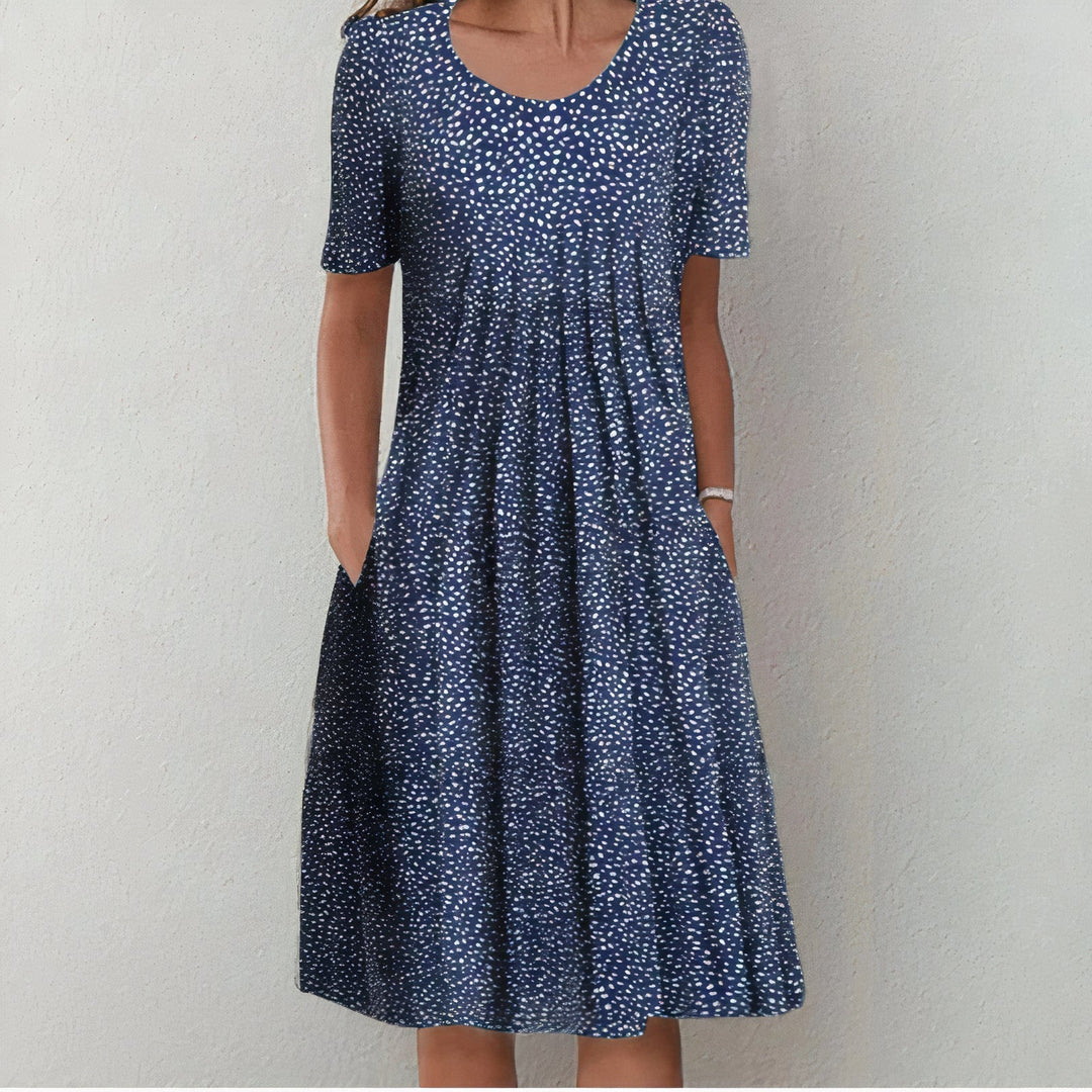 Navy blue dress with small white dots in a studio setting.